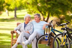 Senior couple takes a break on a park bench while out for a bike ride.